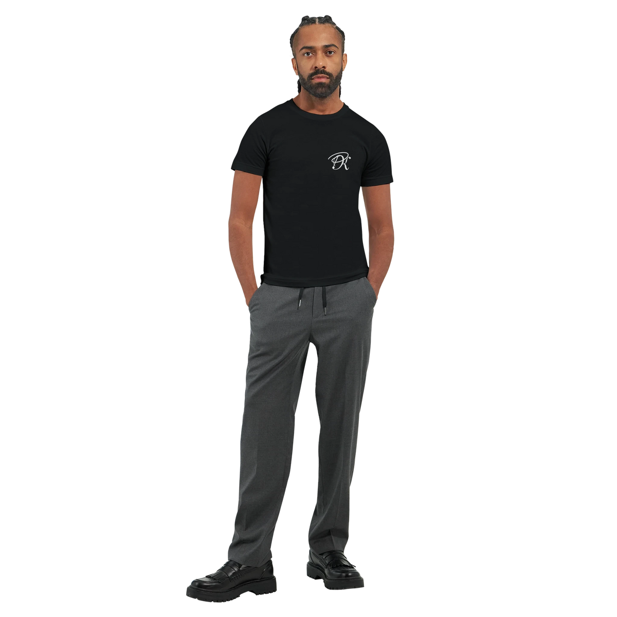 Male model wearing a black “Color the Grey” unisex T-shirt with a subtle white PK monogram on the front, styled with grey trousers in a clean full-body look.