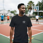 Male model wearing a black unisex statement T-shirt with a small white PK monogram on the chest, styled in a casual outdoor streetwear setting.