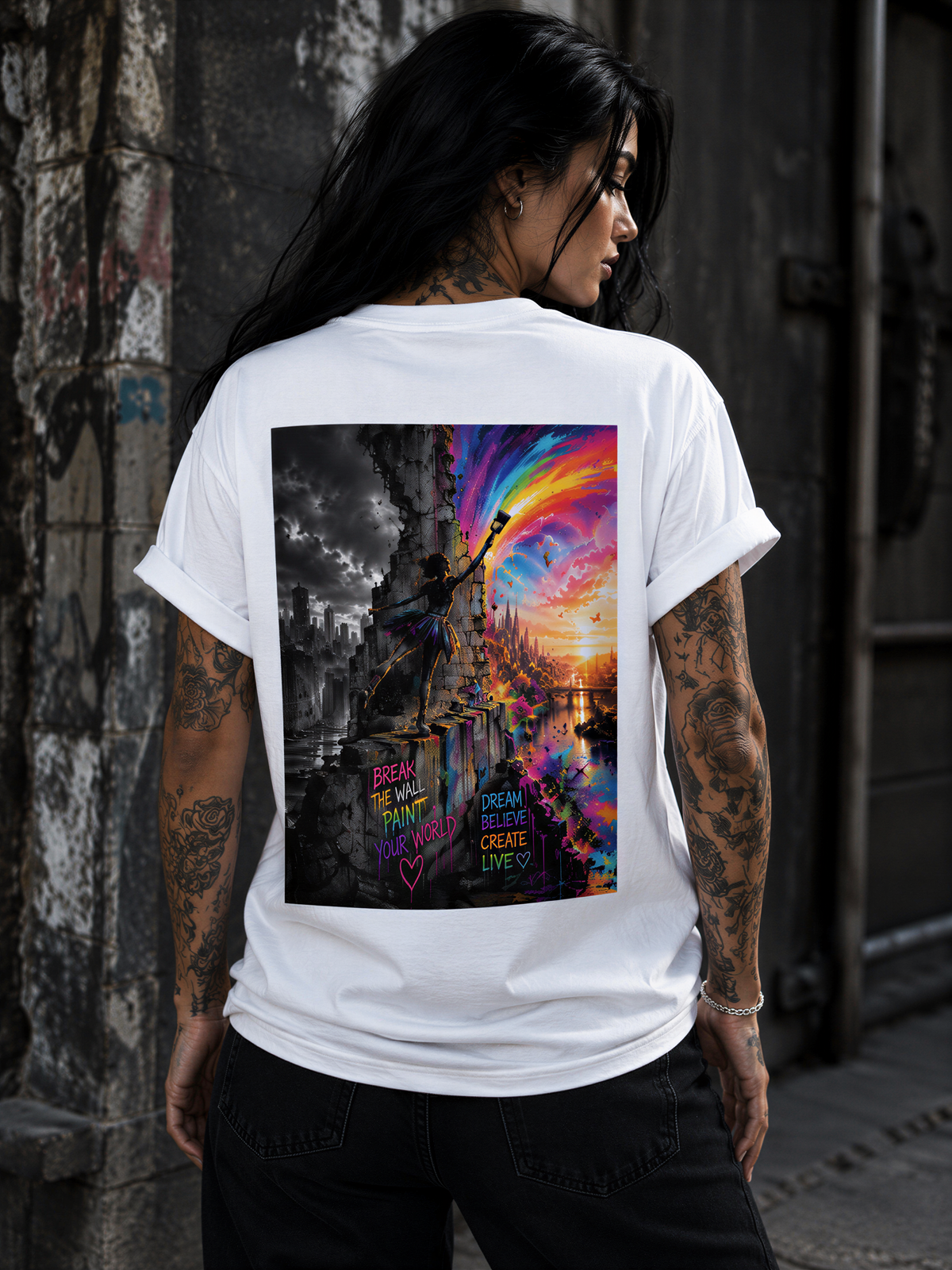 A person with tattoos on their back is wearing a white t-shirt with a colorful graphic design depicting a cityscape at sunset.