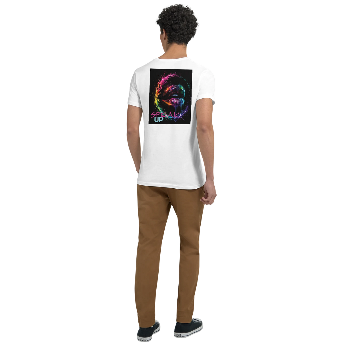 Young man shown from the back wearing a white T-shirt with a colorful neon lips “SPEAK UP” graphic, paired with brown pants and dark sneakers.