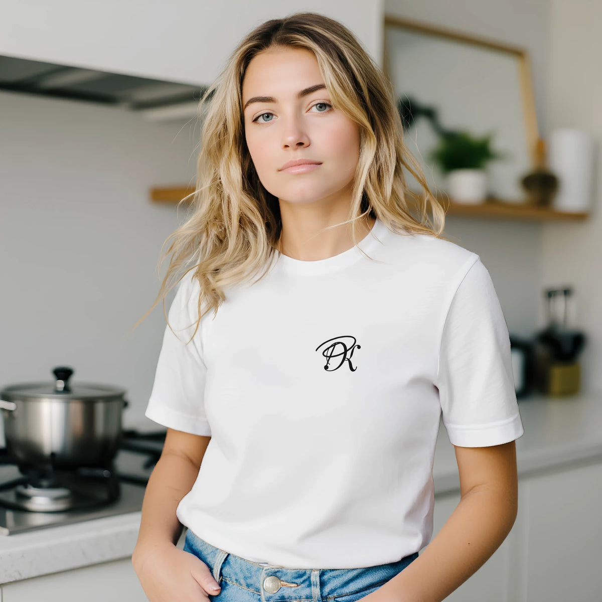 Female model wearing a white T-shirt with a small black PK logo on the chest, styled with blue jeans setting for a clean, casual streetwear look.