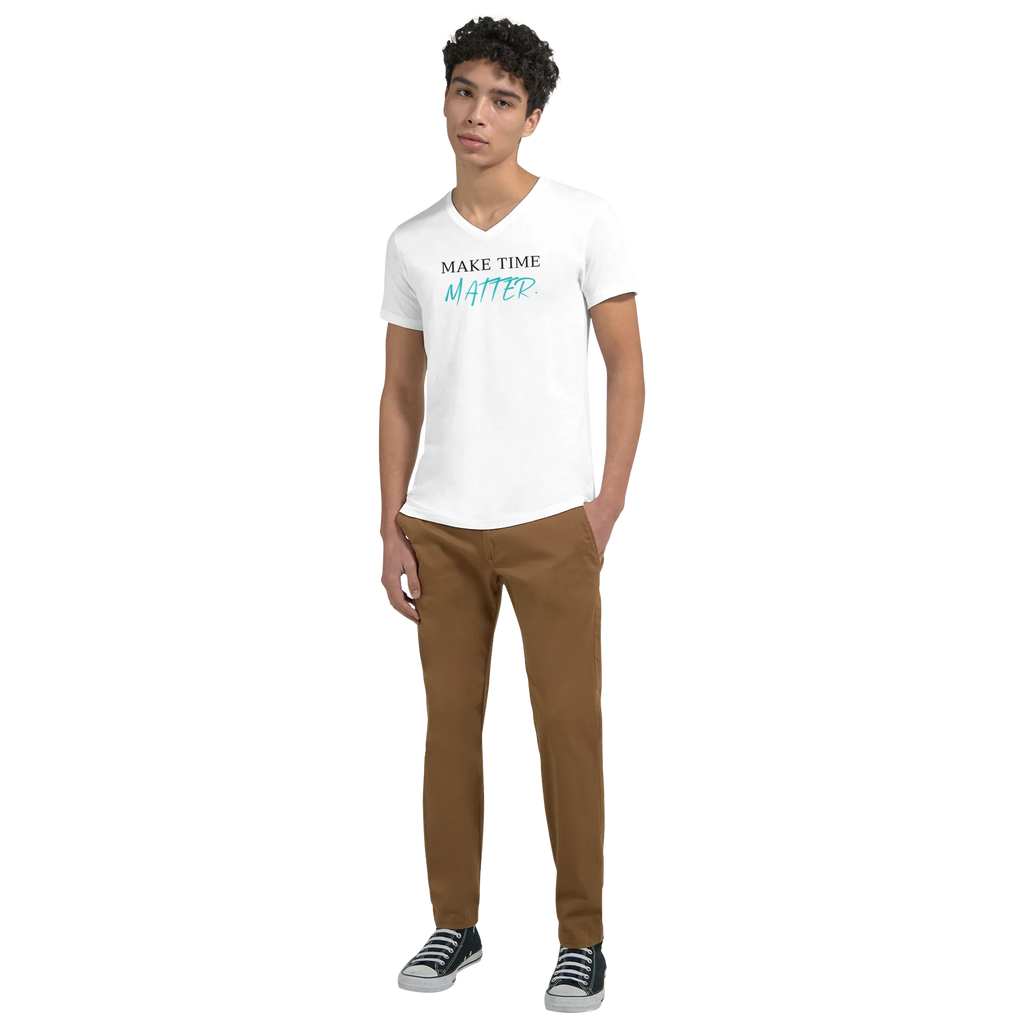 Full-body lifestyle mockup of a model wearing a white V-neck T-shirt featuring the motivational quote ‘MAKE TIME MATTER’ in black serif and turquoise handwritten typography, styled with casual pants and sneakers.