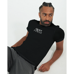 Male model reclining in a black unisex T-shirt featuring the small white “QUIET POWER” chest print.