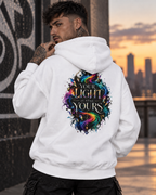 Tattooed men wearing a white hoodie featuring the colorful “Your Light Is Still Yours” back print, photographed in an urban setting at sunset.