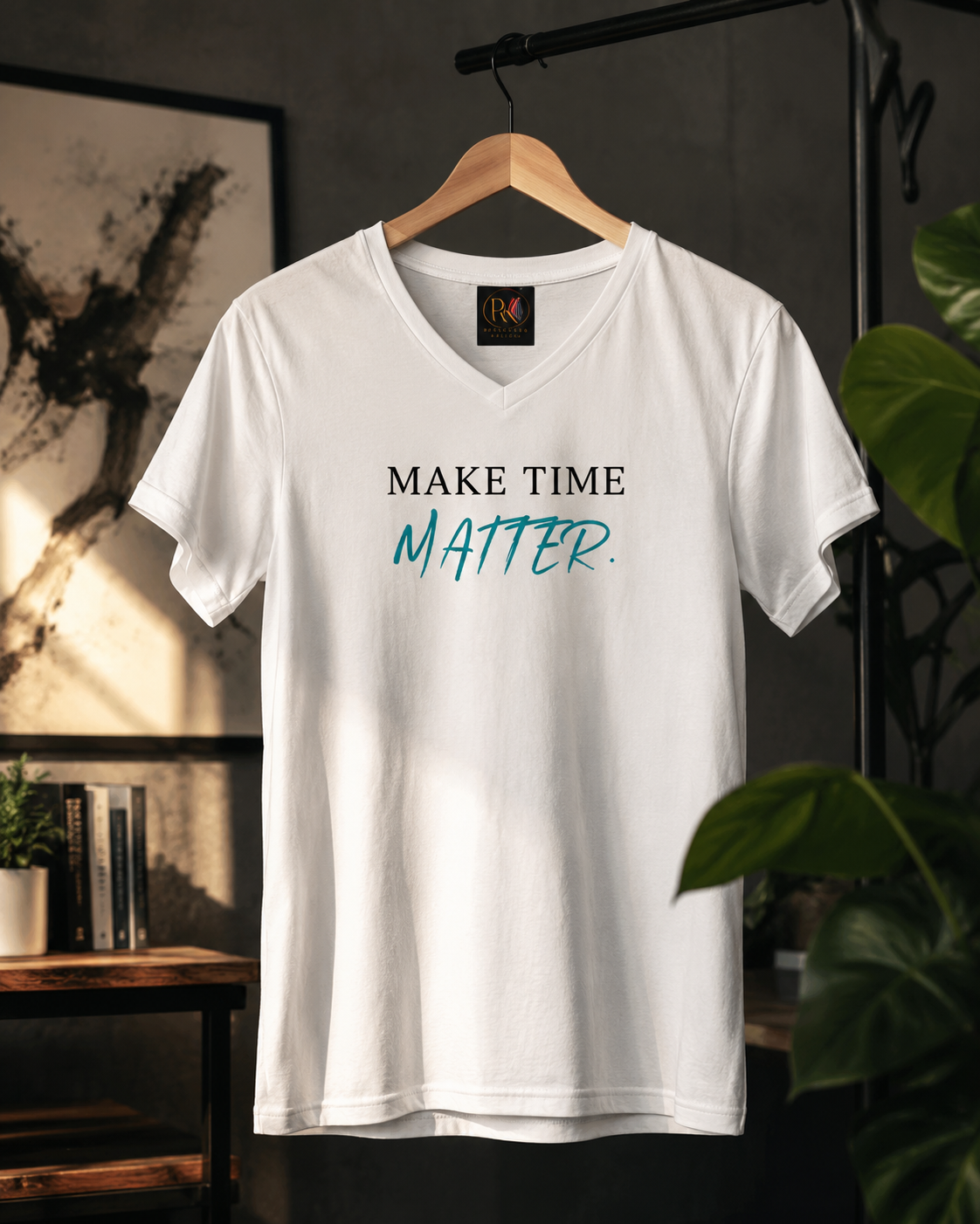 White premium unisex V-neck T-shirt hanging on a wooden hanger in a modern interior. The front features the minimalist statement 'MAKE TIME MATTER.' in black and turquoise typography, creating a clean, motivational design that encourages living intentionally and making every moment count.